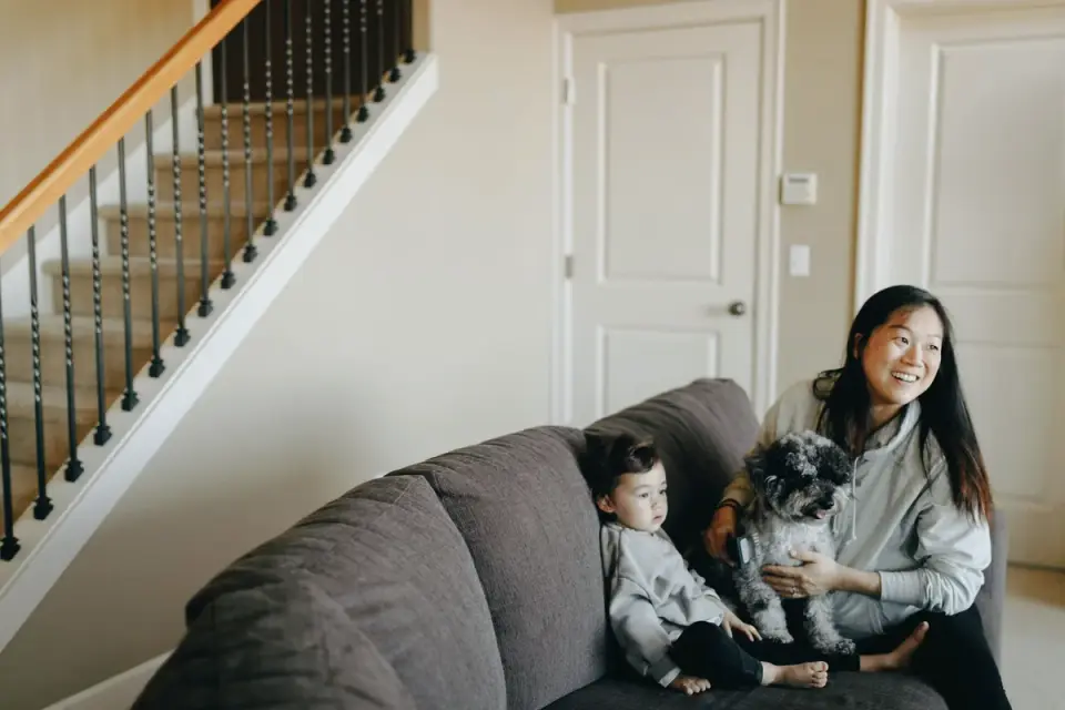 A family sitting on a couch petting a Goldendoodle