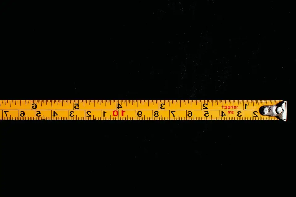 A person holding a tape measure against a dog's back to determine crate size